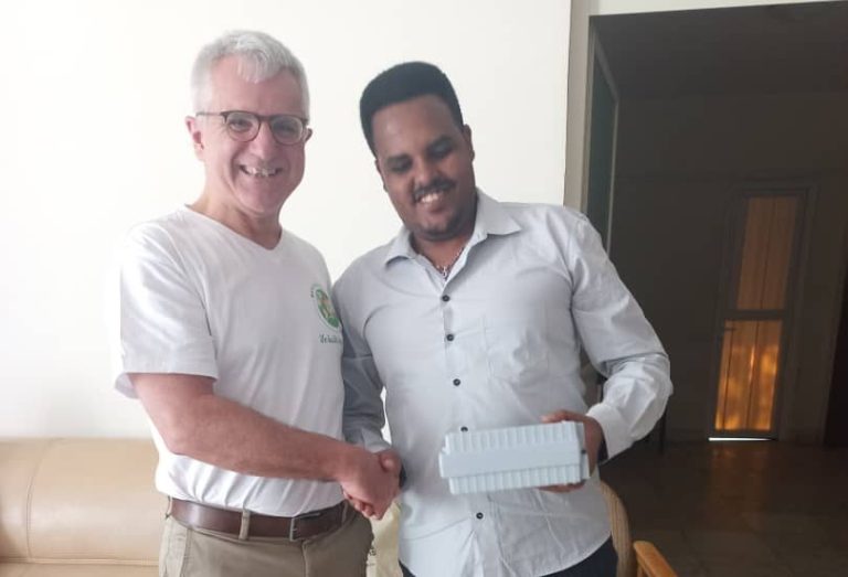 Dr. Jeronimo Sequice steht neben einem Plakat der GTP Tagung. 