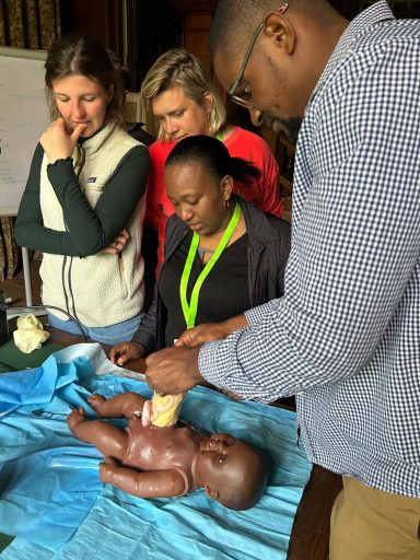 Fünf Personen bei einer praktischen Schulung zur Säuglingsversorgung.